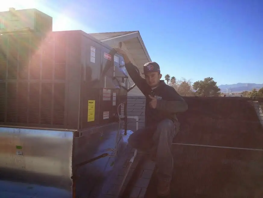 HVAC technician performing Heat Pump Repair on a rooftop unit in Peterborough